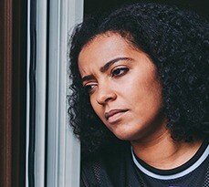 An unhappy woman looking out of a window.