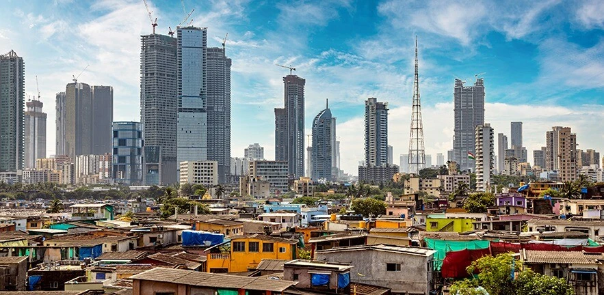 Views of slums on the shores of Mumbai, India against the backdrop of skyscrapers under construction.