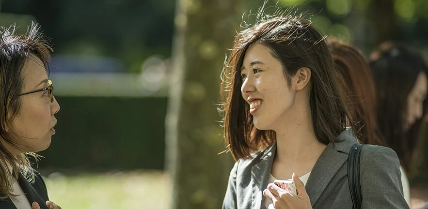 A female MBA student chats to a colleague in the sunshine.