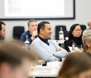 Group of men and women listening intently in a classroom.