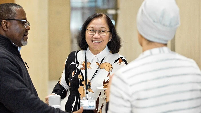 Two women and a man engaged in conversation and smiling.