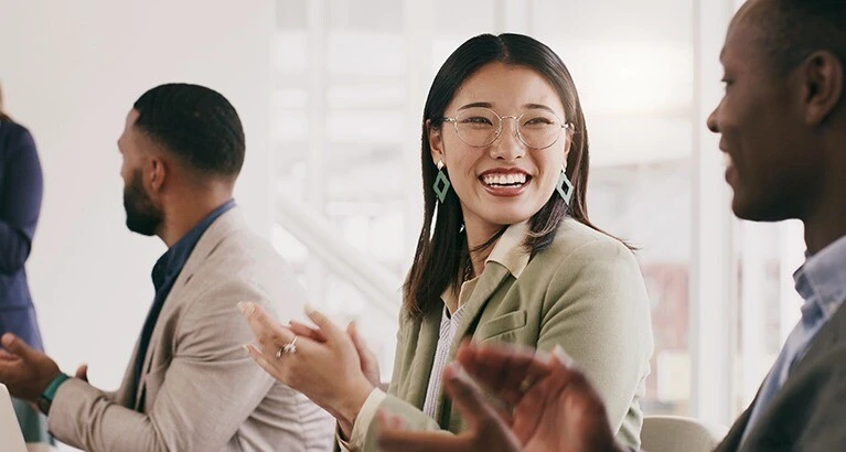 Colleagues clapping in and laughing in the workplace.