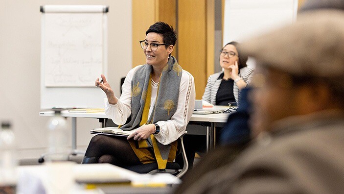 Woman engaging in conversation in a classroom.