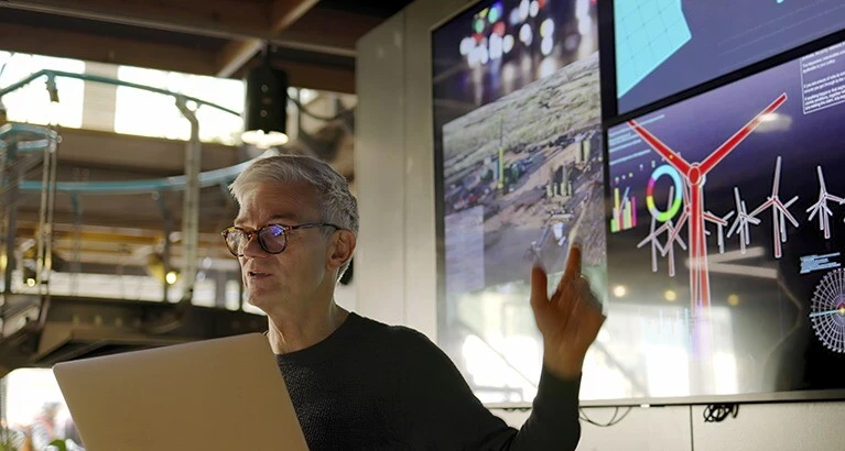 Mature man presents about wind turbines to a company board.