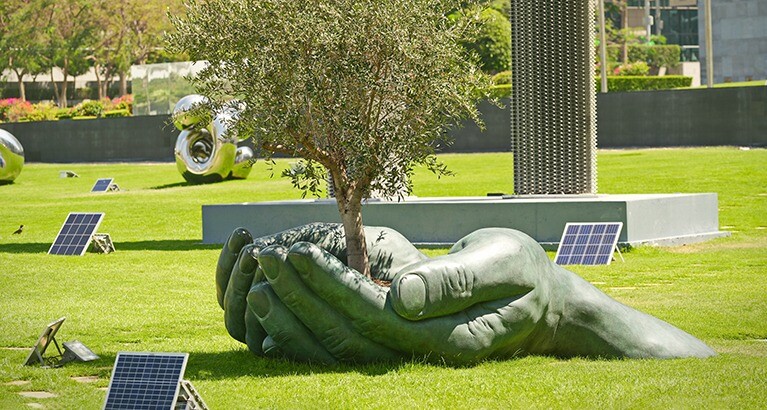 Hands holding tree sculpture in Dubai.