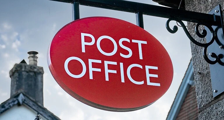 An old fashioned Post Office sign hanging outside a main street Post Office.