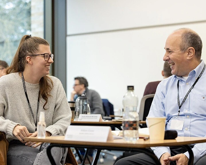 A man and a woman smiling at each other in a classroom.