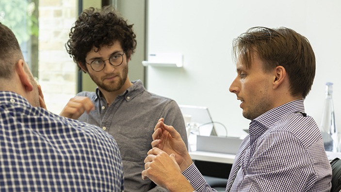 Two men engaging in conversation in a classroom.